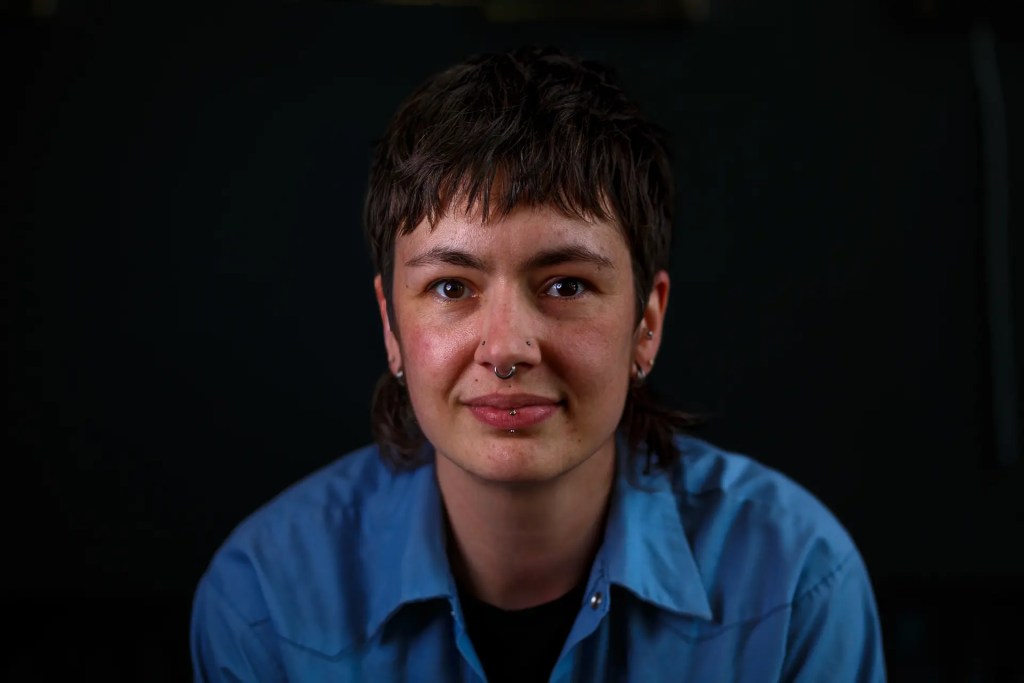 Barber Lucy Thomas posing for a professional headshot at Shear Barber Studio in Olympia, WA, by Russell Moore Photography.